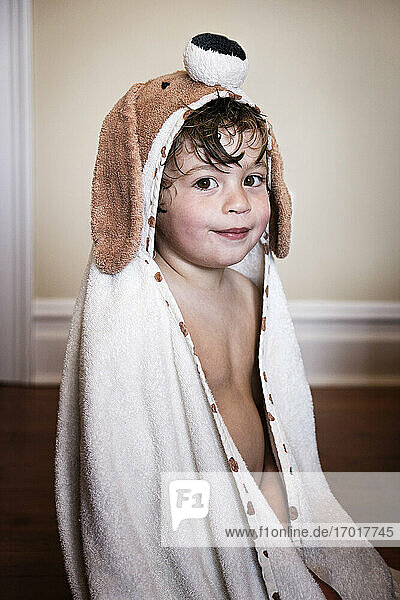 Smiling boy after bath wearing dog towel
