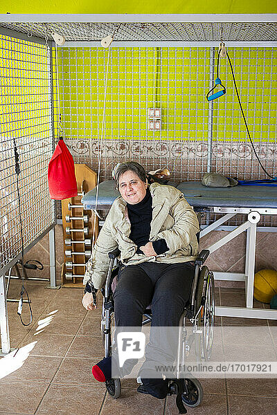 Mature disabled woman sitting on wheelchair exercising with rope at rehabilitation center