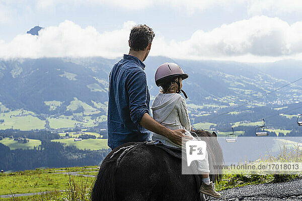 Vater geht neben seiner kleinen Tochter  die auf einem Pony reitet  durch ein Bergtal