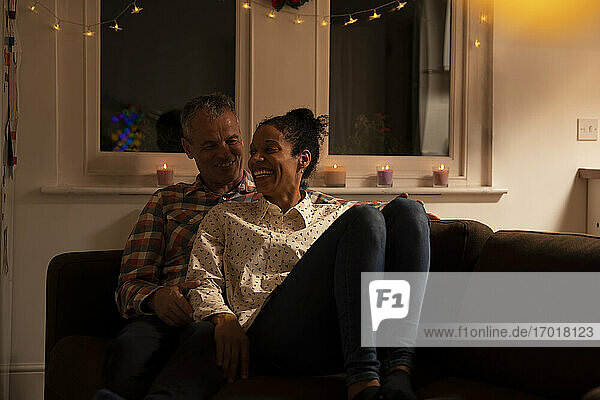 Smiling couple talking while relaxing on sofa at home