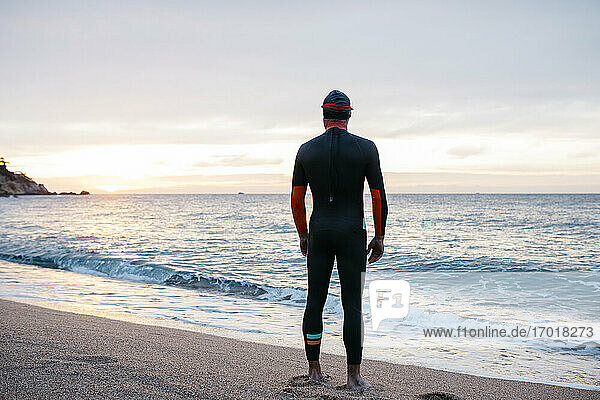 Männlicher Schwimmer bewundert das Meer bei Sonnenuntergang