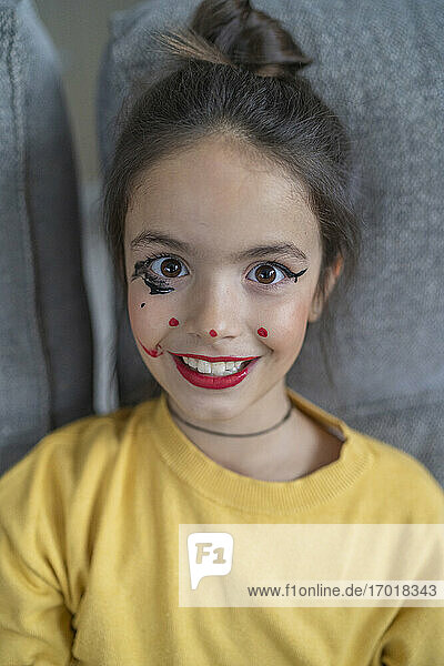 Kleines Mädchen mit Make-up sitzt zu Hause
