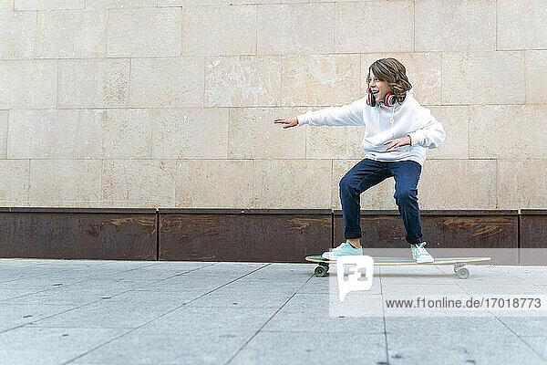 Carefree boy skateboarding on footpath