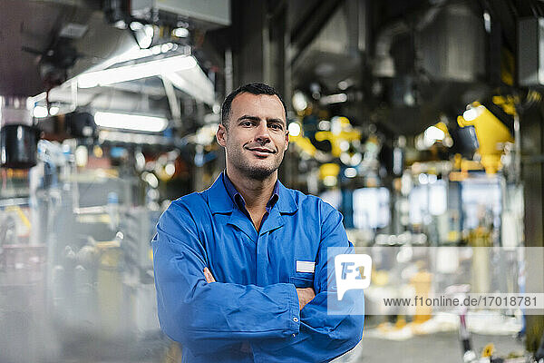 Smiling male engineer with arms crossed standing in factory