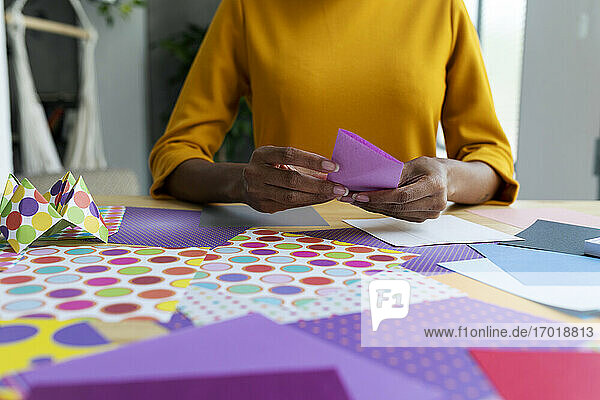 Origami-Künstlerin sitzt im Atelier und faltet buntes Papier