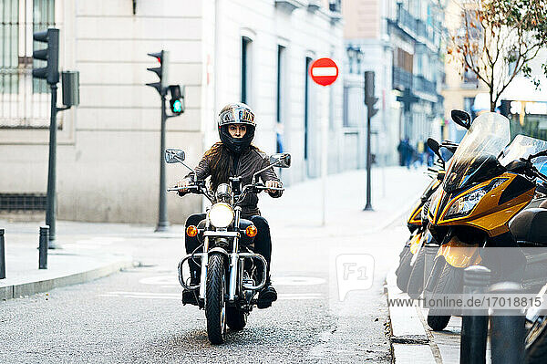 Motorradfahrerin mit Helm auf einer Straße in der Stadt