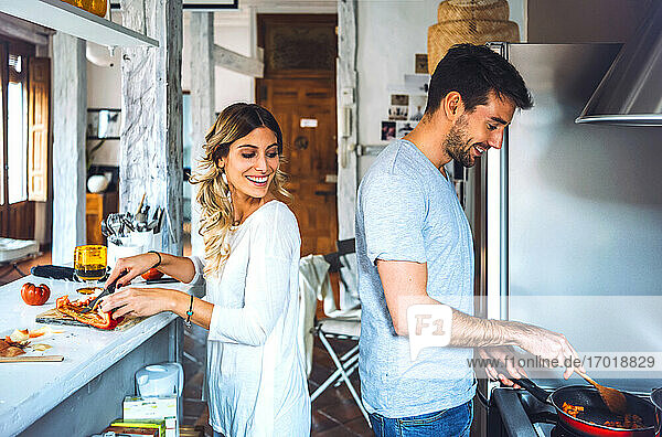 Happy young couple preparing food together in kitchen at home