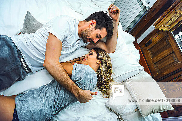 Zärtliches junges Paar kuschelt zu Hause im Bett