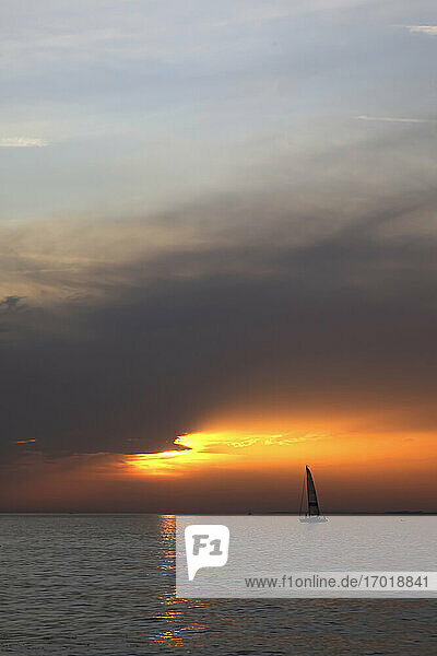 Silhouette of sailboat sailing in Lake Constance at moody sunset