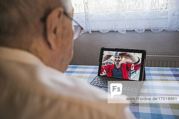 Großvater spricht mit Enkelin per Videoanruf über Laptop zu Hause