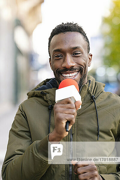 Nahaufnahme eines lächelnden männlichen Moderators  der über ein Mikrofon spricht