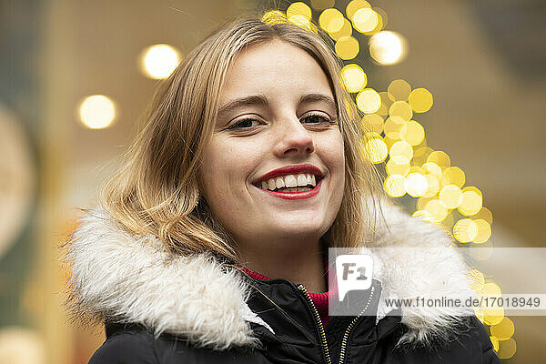 Bindung junge Frau lächelnd gegen Weihnachtsbeleuchtung während der Feiertage
