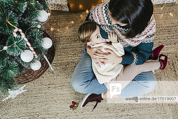 Mutter  die ihre Tochter stillt  während sie zu Hause sitzt  während Weihnachten