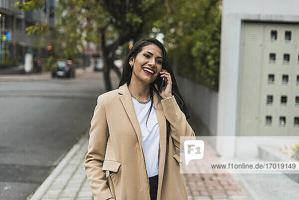 Attraktive Frau im Gespräch über Smartphone auf dem Fußweg in der Stadt