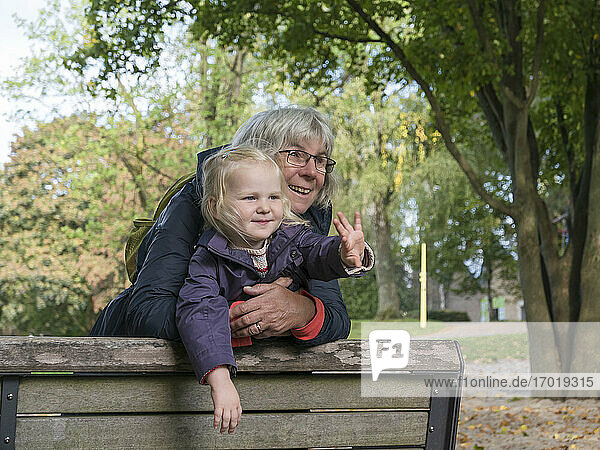 Großmutter und Enkelin lehnen auf einer Bank und schauen in einem öffentlichen Park weg