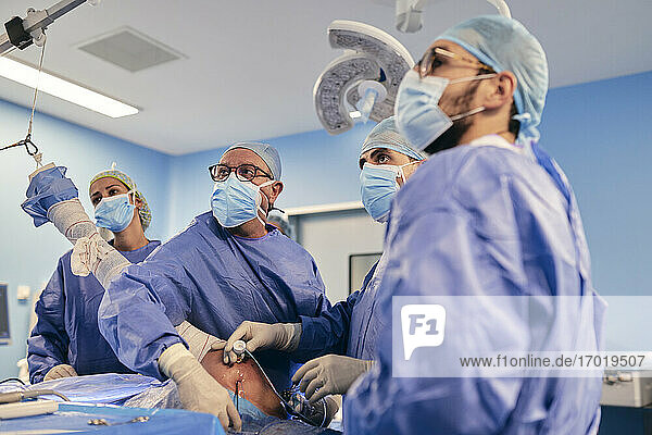 Fachkräfte  die eine arthroskopische Operation an der Schulter durchführen  während sie im Operationssaal bei COVID-19 stehen