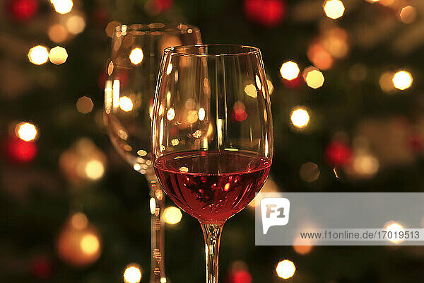 Rose wine in shiny wineglass in front of Christmas tree