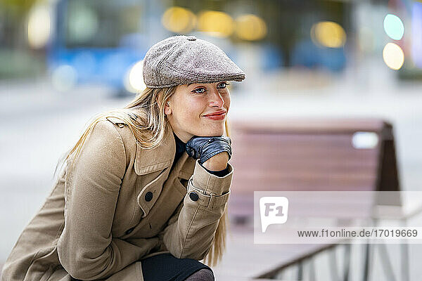 Smiling woman with hand on chin sitting on bench