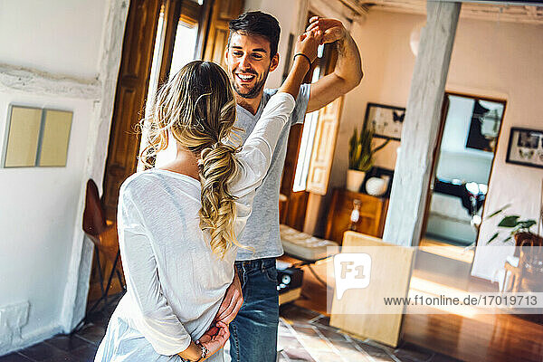 Glückliches junges Paar tanzt im Wohnzimmer zu Hause