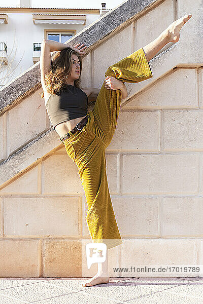 Junge Frau tanzt an einer Steinmauer im Freien
