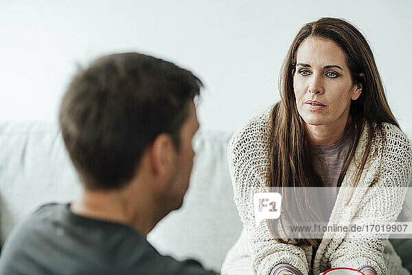 Mature woman with gray eyes looking at man while sitting at home