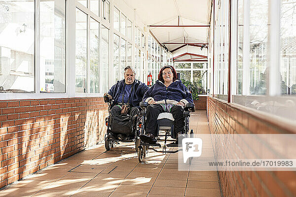 Disabled man and woman on wheelchair in corridor
