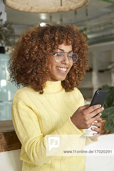 Lächelnde Frau mit Smartphone in einem Café