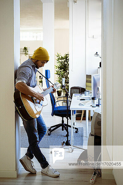 Guitarist playing guitar while standing at studio