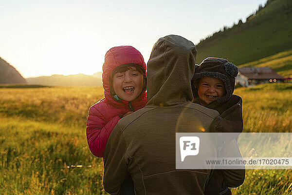 Mutter mit zwei fröhlichen Kindern auf einem landwirtschaftlichen Feld bei Sonnenuntergang in den Ferien am Col Des Aravis  Haute-Savoie  Frankreich