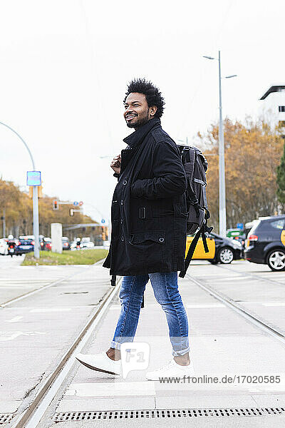 Hipster Mann mit Rucksack zu Fuß auf der Straße gegen klaren Himmel
