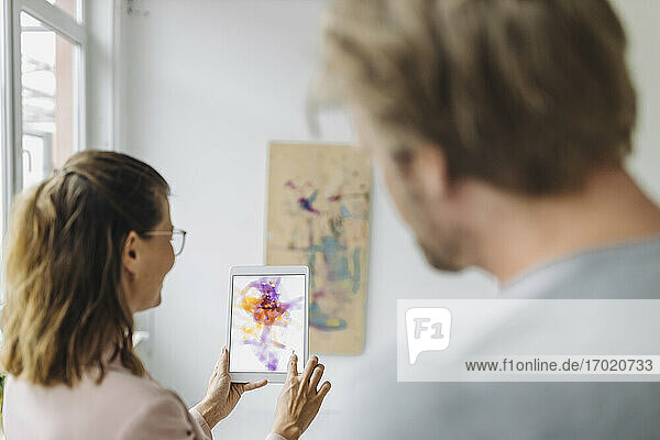 Frau und Mann benutzen digitales Tablet in einer Kunstgalerie