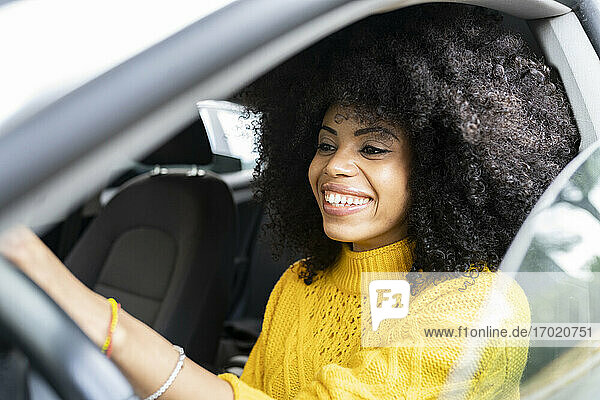 Curly hair woman smiling while driving car