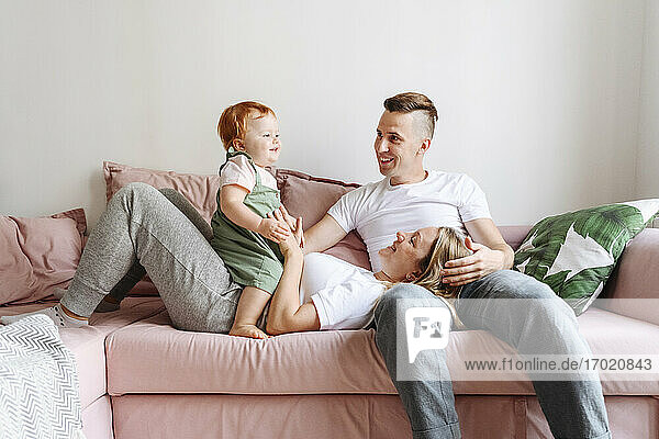 Happy family with baby daughter relaxing on sofa