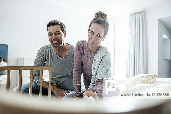 Mature man and woman playing by crib in apartment