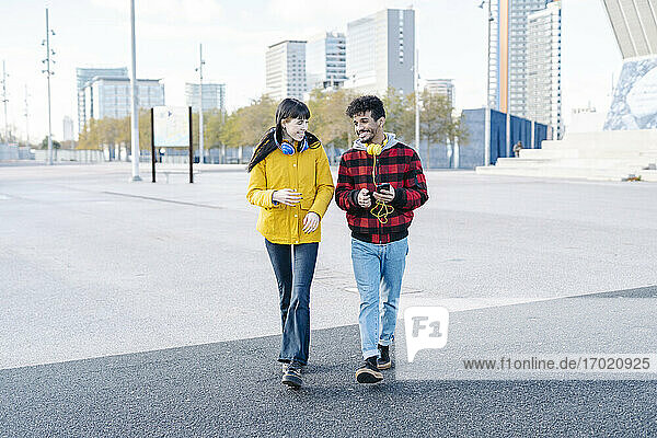 Junges Paar lächelnd beim Spaziergang auf der Straße in der Stadt