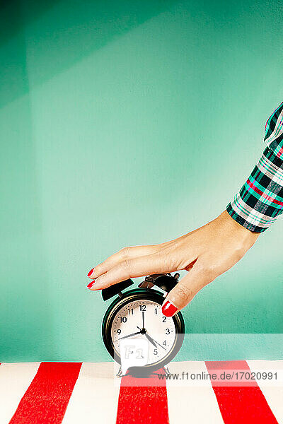 Hand of woman turning off old-fashioned alarm clock