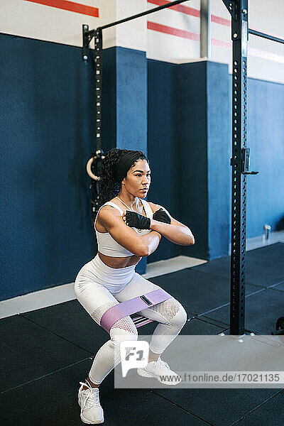 Confident female athlete working out with resistance band in gym