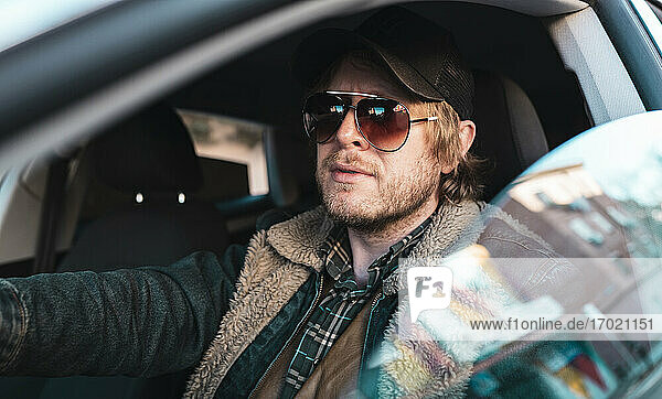 Mann mit Sonnenbrille im Auto sitzend durch Fenster gesehen
