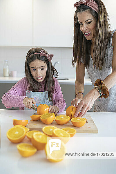Mother and daughter cutting oranges kitchen
