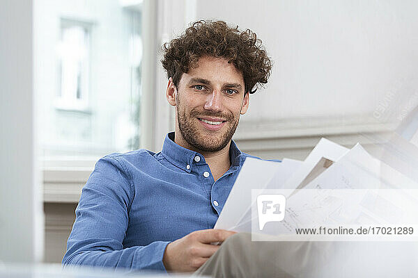 Lächelnder Geschäftsmann mit Dokument im Büro