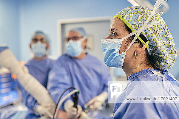 Ärztin mit Gesichtsschutzmaske steht mit einem Kollegen im Operationssaal eines Krankenhauses