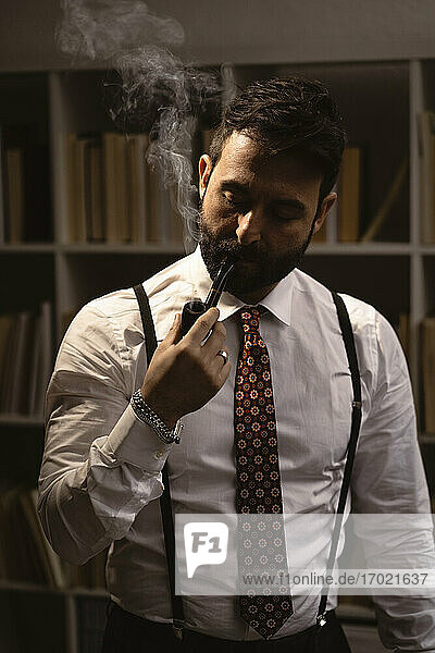 Portrait of bearded man smoking pipe 