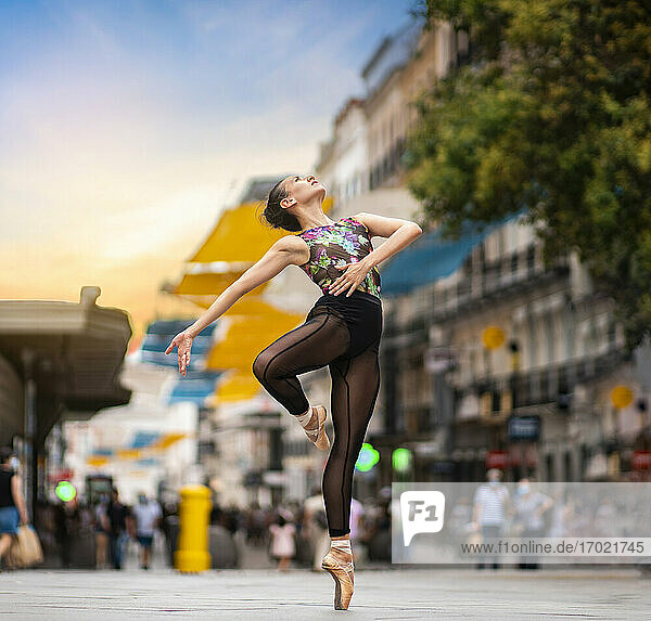 Tänzerin übt Ballett tanzen  während stehend Zehenspitzen auf der Straße in der Stadt bei Sonnenuntergang