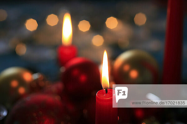 Red burning advent candles and Christmas baubles