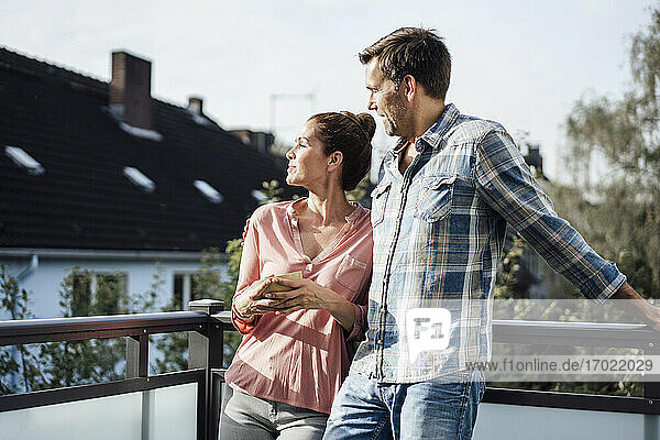 Mature couple spending leisure time together in balcony on sunny day