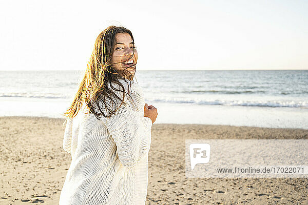 Fröhliche schöne Frau verbringt ihre Freizeit am Strand während eines sonnigen Tages