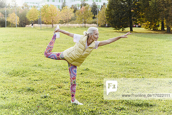 Ältere Frau macht Yoga-Übungen auf Gras in einem öffentlichen Park