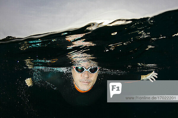 Männlicher Schwimmer  der beim Tauchen im Meer in die Kamera schaut