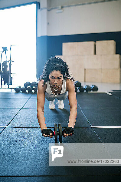 Female athlete exercising with abdominal toning wheel in gym