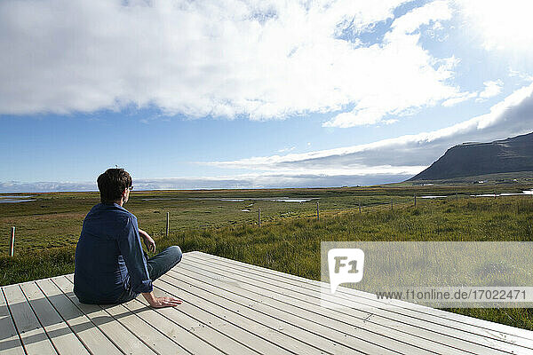 Man looking at view while sitting on terrace at Flokalundur  Iceland